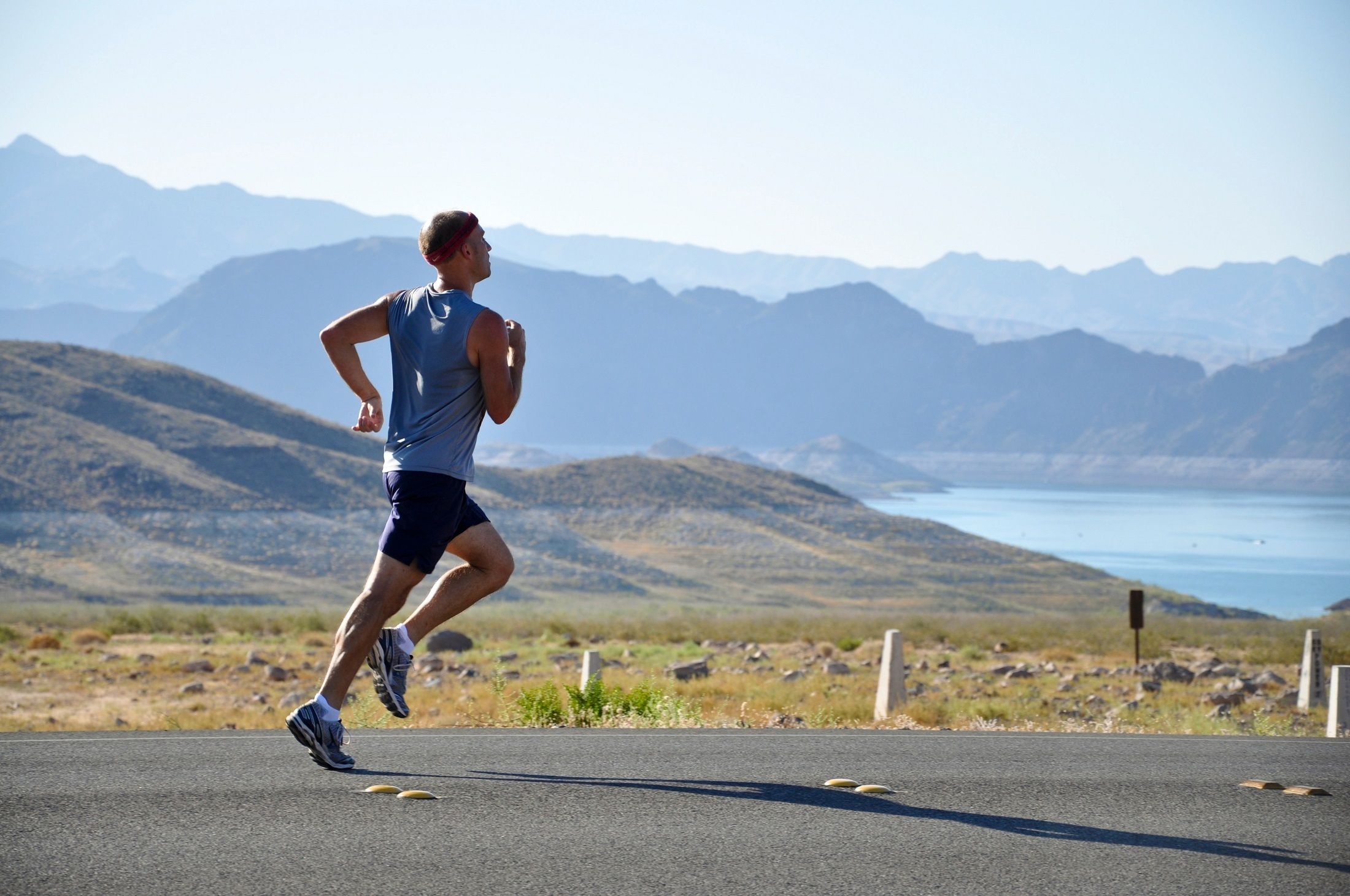 A runner on a quiet lakeside trail with mountains in the distance