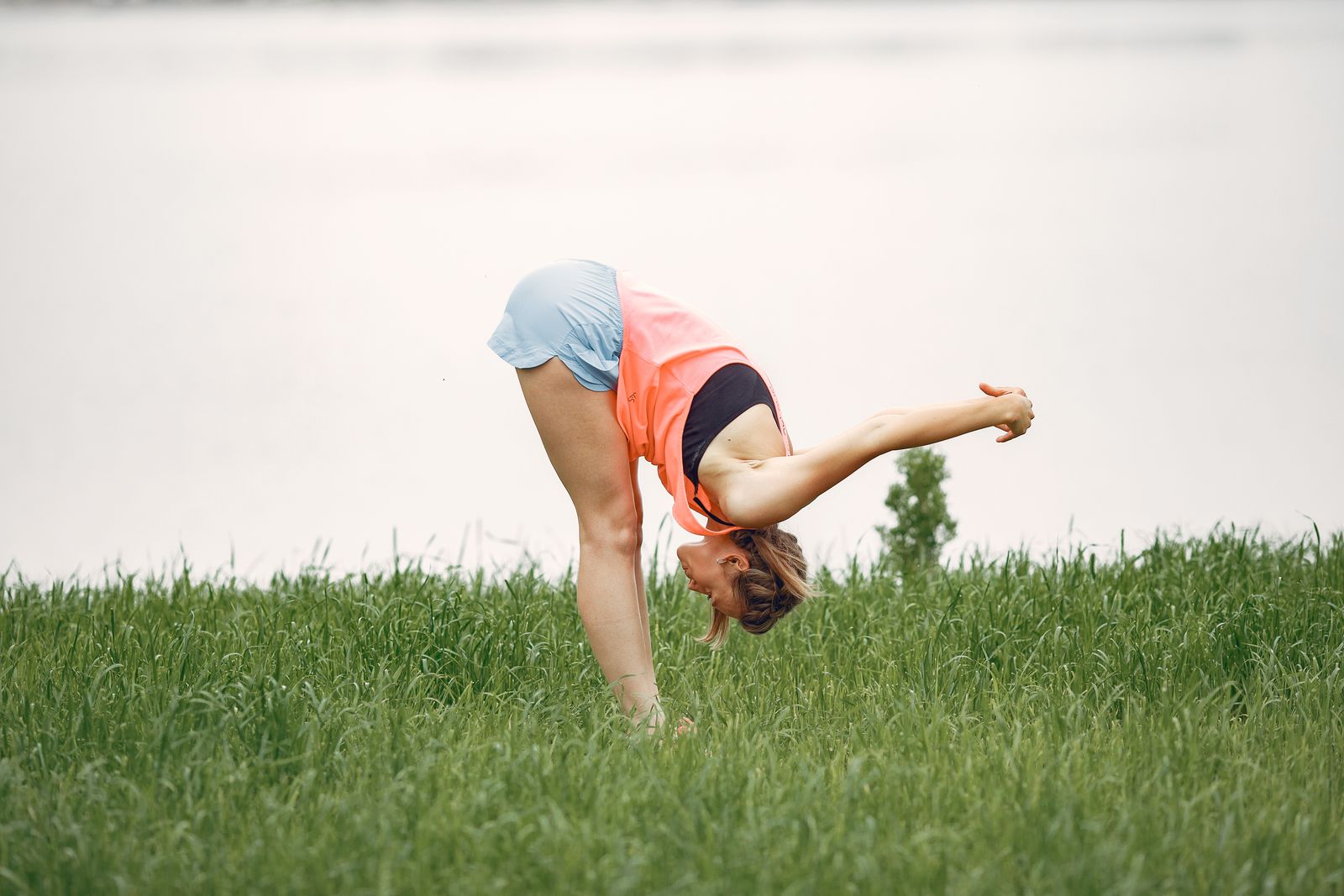 An active woman stretching outdoors in a green field